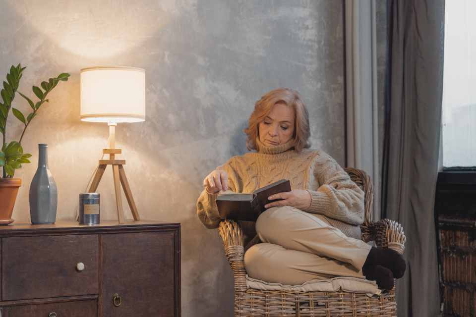 woman reading in living room next to table lamp